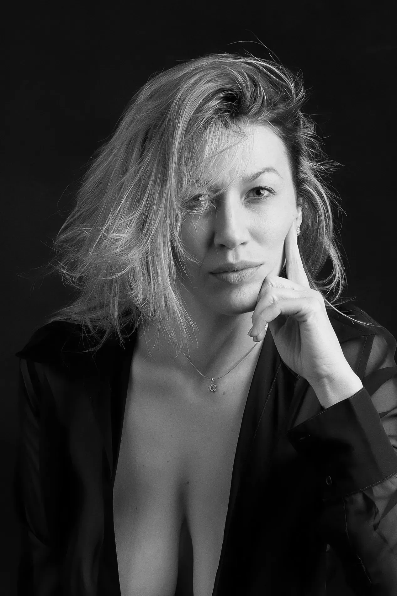 Séance boudoir captivante par TRIFA Studio, mettant en vedette une magnifique modèle aux cheveux blonds, posant avec élégance dans une tenue raffinée semi-transparente noire. L'image en noir et blanc accentue la sensualité et le glamour, avec un fond sombre qui met en valeur chaque détail de sa silhouette et son regard énigmatique. Contactez TRIFA Studio pour une expérience photographique d’exception et des clichés intemporels ! #TRIFAStudio #SéanceBoudoir #PhotographieArtistique