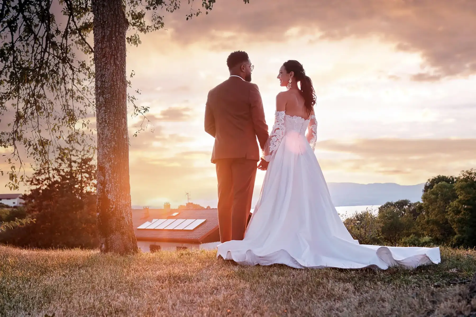 Photo de mariage par TRIFA Studio près du Lac Léman (Lake Geneva). Couple en tenue élégante face à un coucher de soleil, avec le lac en arrière-plan.
